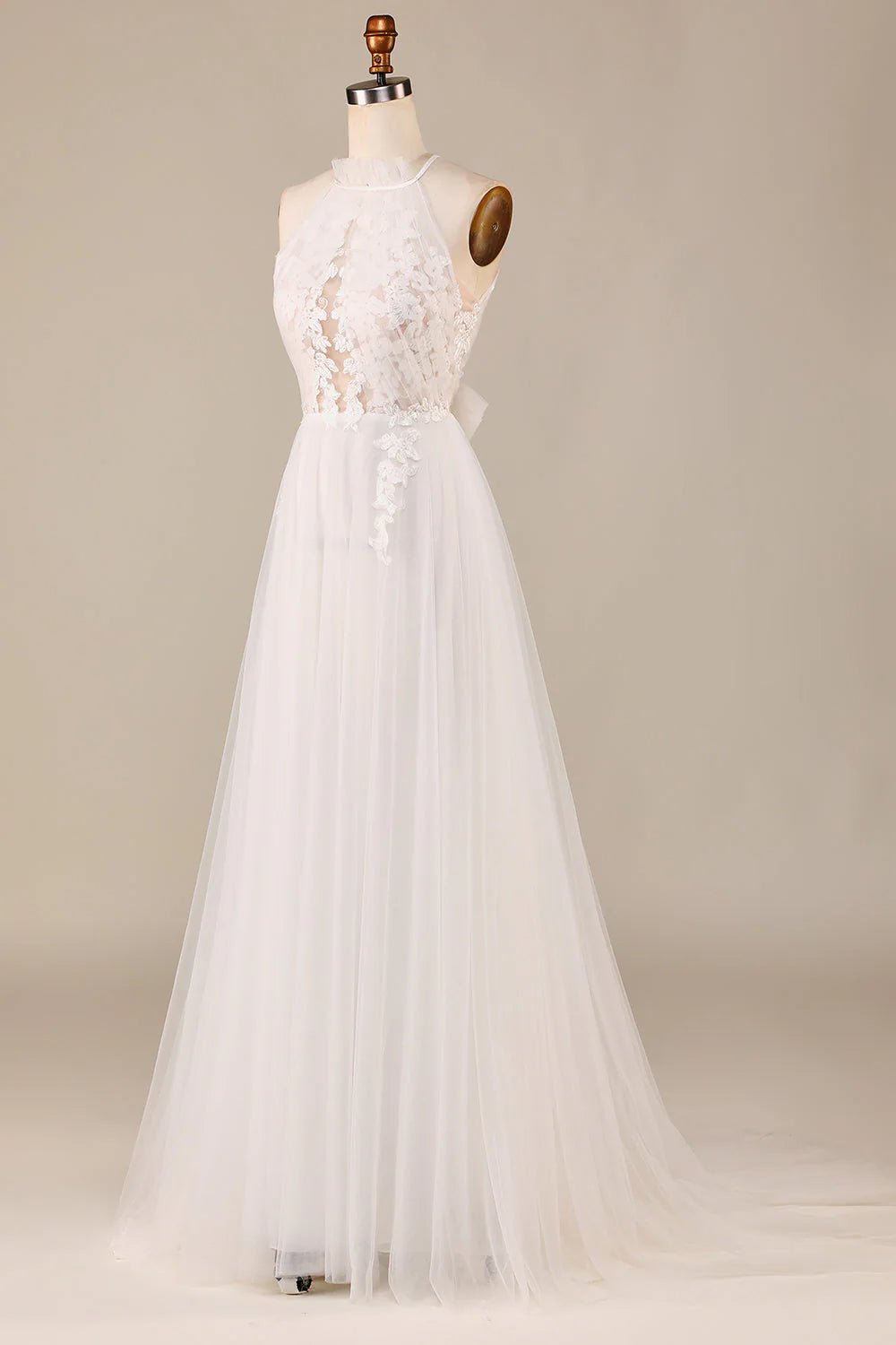 Un grazioso abito da sposa in pizzo trasparente color avorio, senza maniche, con scollatura a trapezio e schiena scoperta.